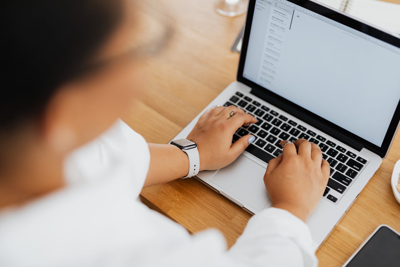 Mastering the First Impression: Your intriguing post title goes here High angle shot of a person typing on a laptop, focused on hands and keyboard.